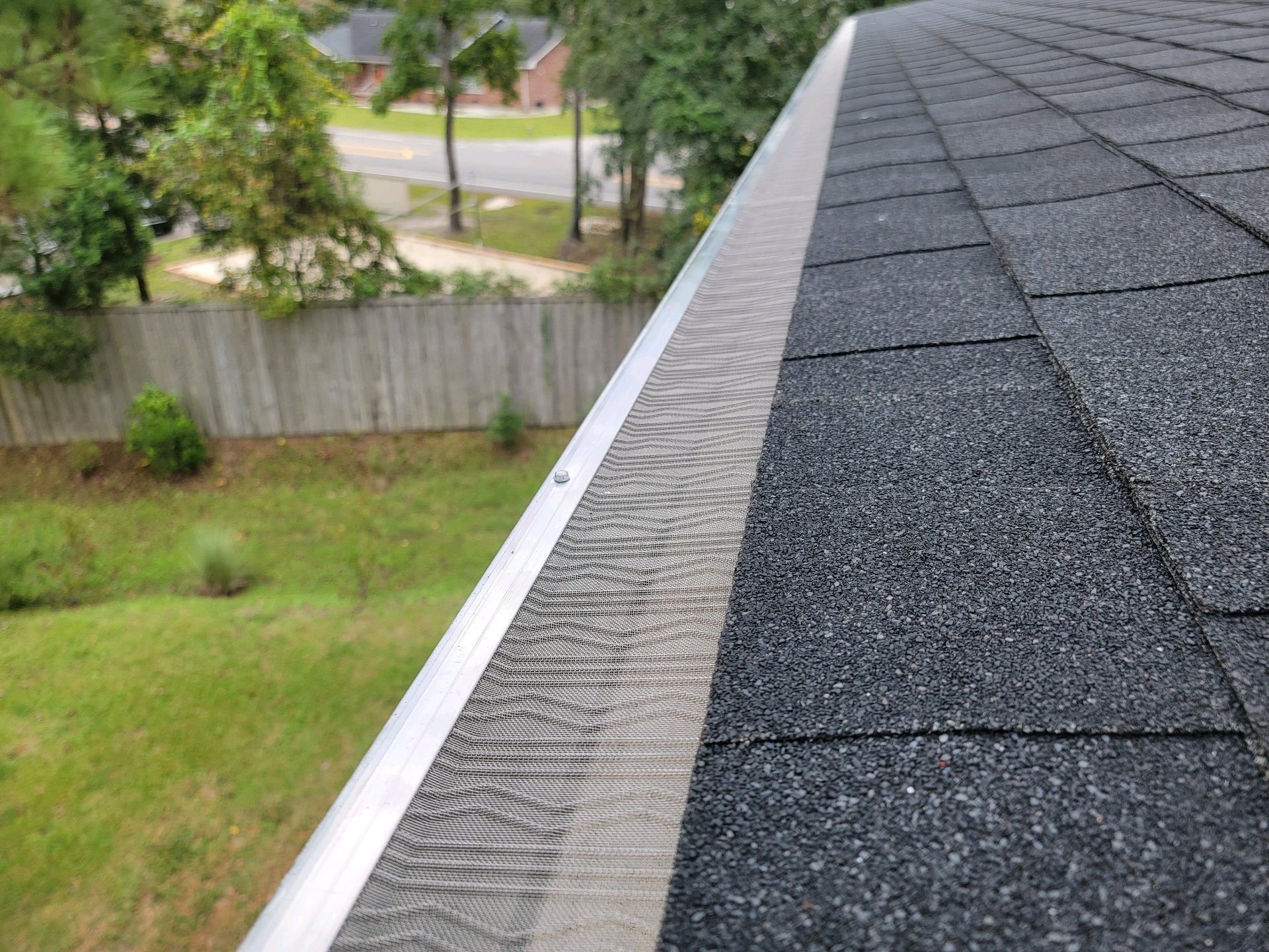 Close view of micro-mesh gutter guards installed beside a shingle roof
